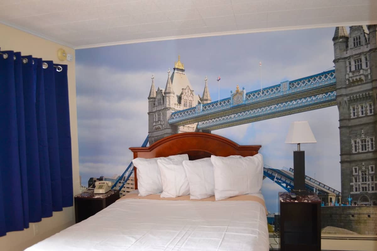 Una habitación de hotel con una cama, una mesita de noche, una lámpara y un mural en la pared de un puente.