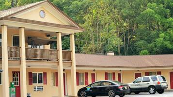 A two-story motel with a balcony on the upper floor, a covered front porch, and a parking area with two cars.