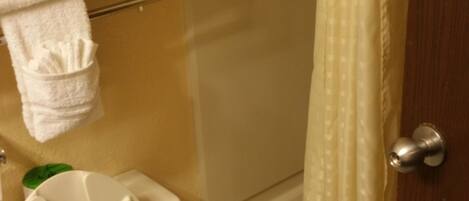 A bathroom with a toilet, a shower curtain, and a bathtub.