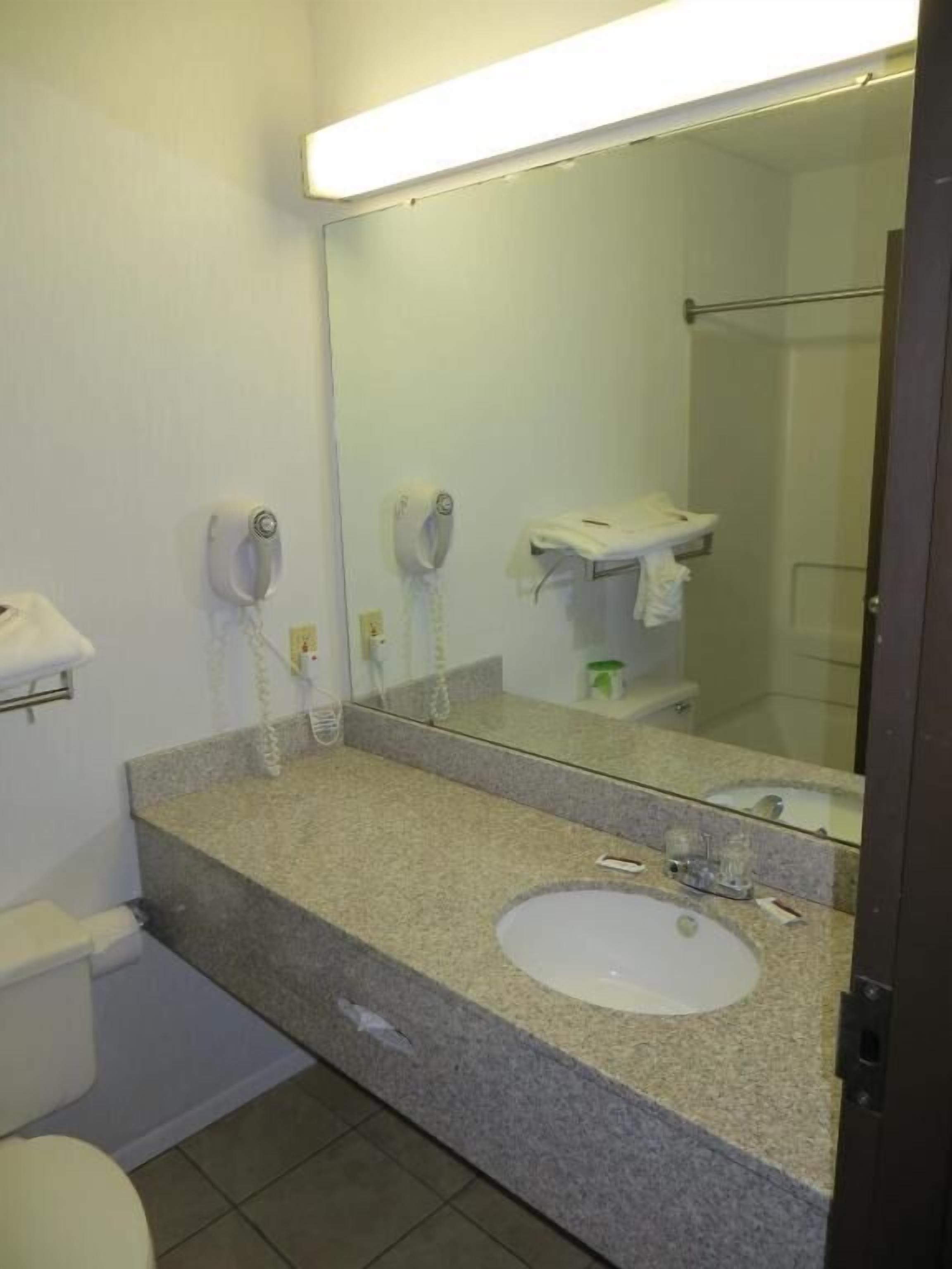A bathroom with a sink, mirror, towel rack, and toilet.