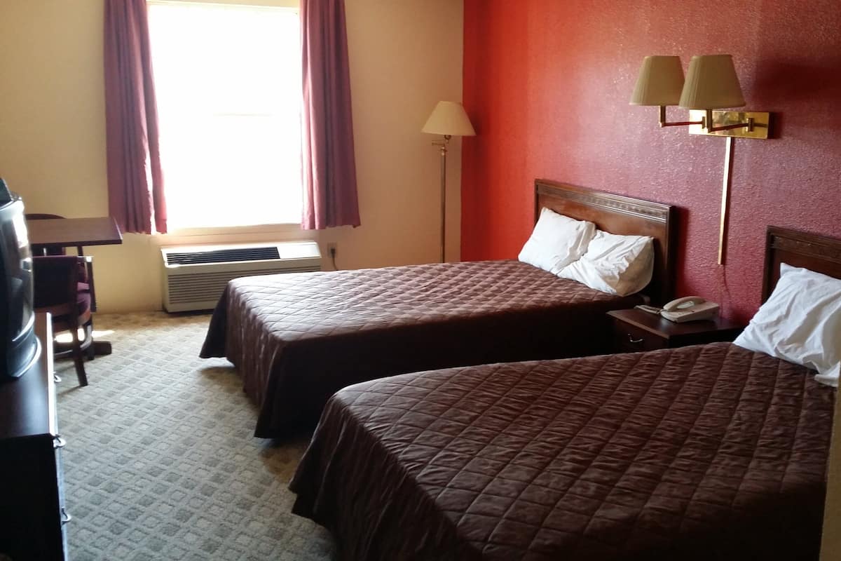 Ein Hotelzimmer mit zwei Betten, einem Schreibtisch, einer Lampe und einem Telefon.