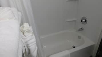 A white bathtub with a shower curtain, a towel, and a small sink.