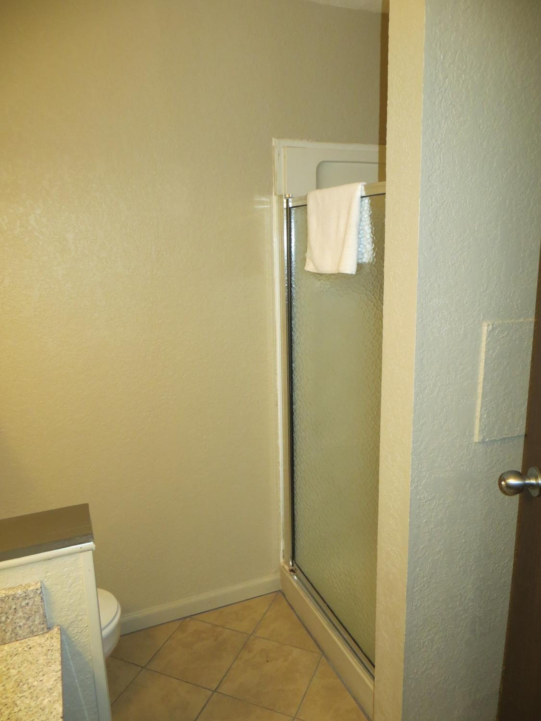 Un baño pequeño con inodoro, cabina de ducha y lavamanos.