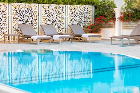 Una piscina al aire libre de temporada, sillones reclinables de piscina
