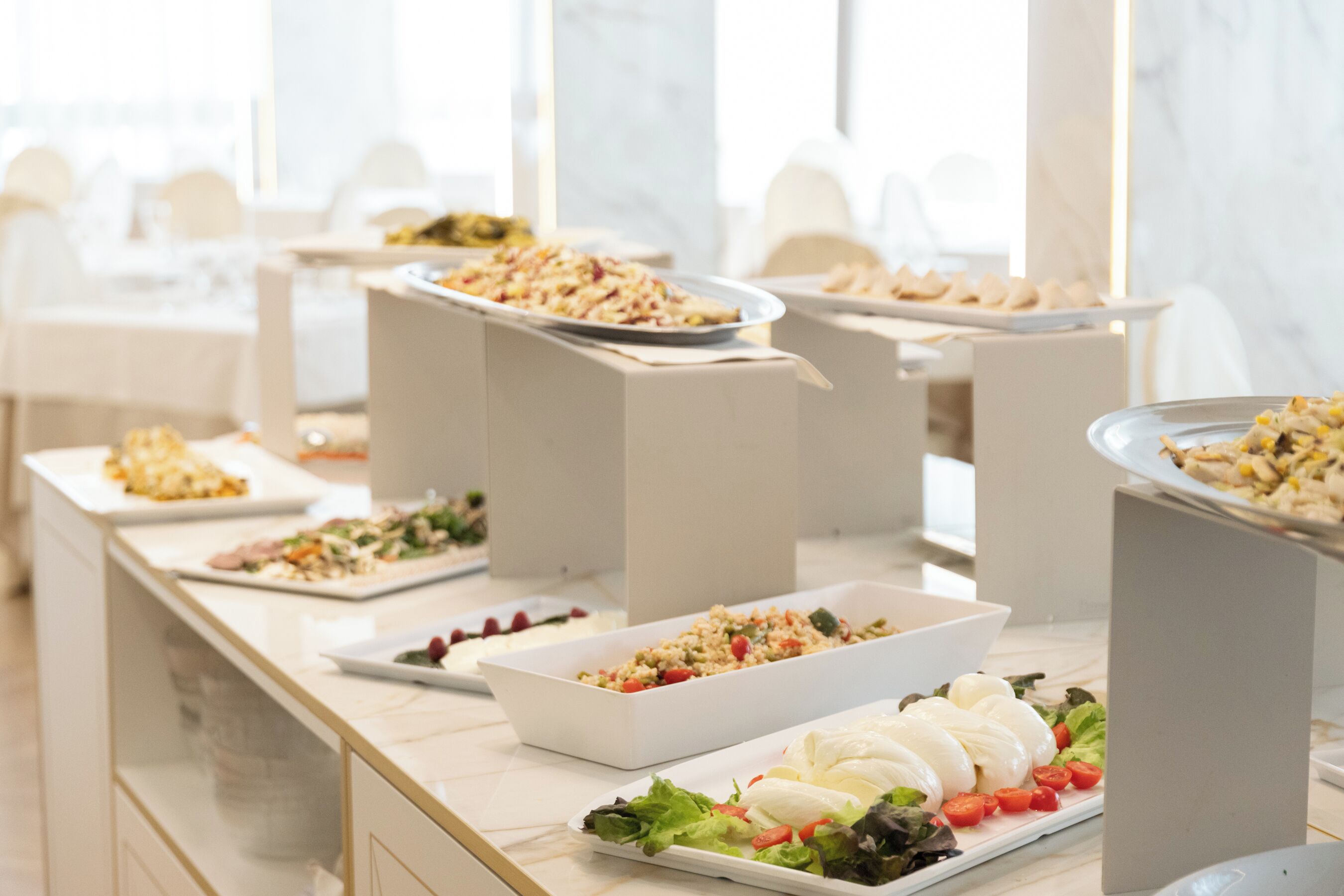 A buffet with various dishes, including salads, pasta, and a selection of cheeses.