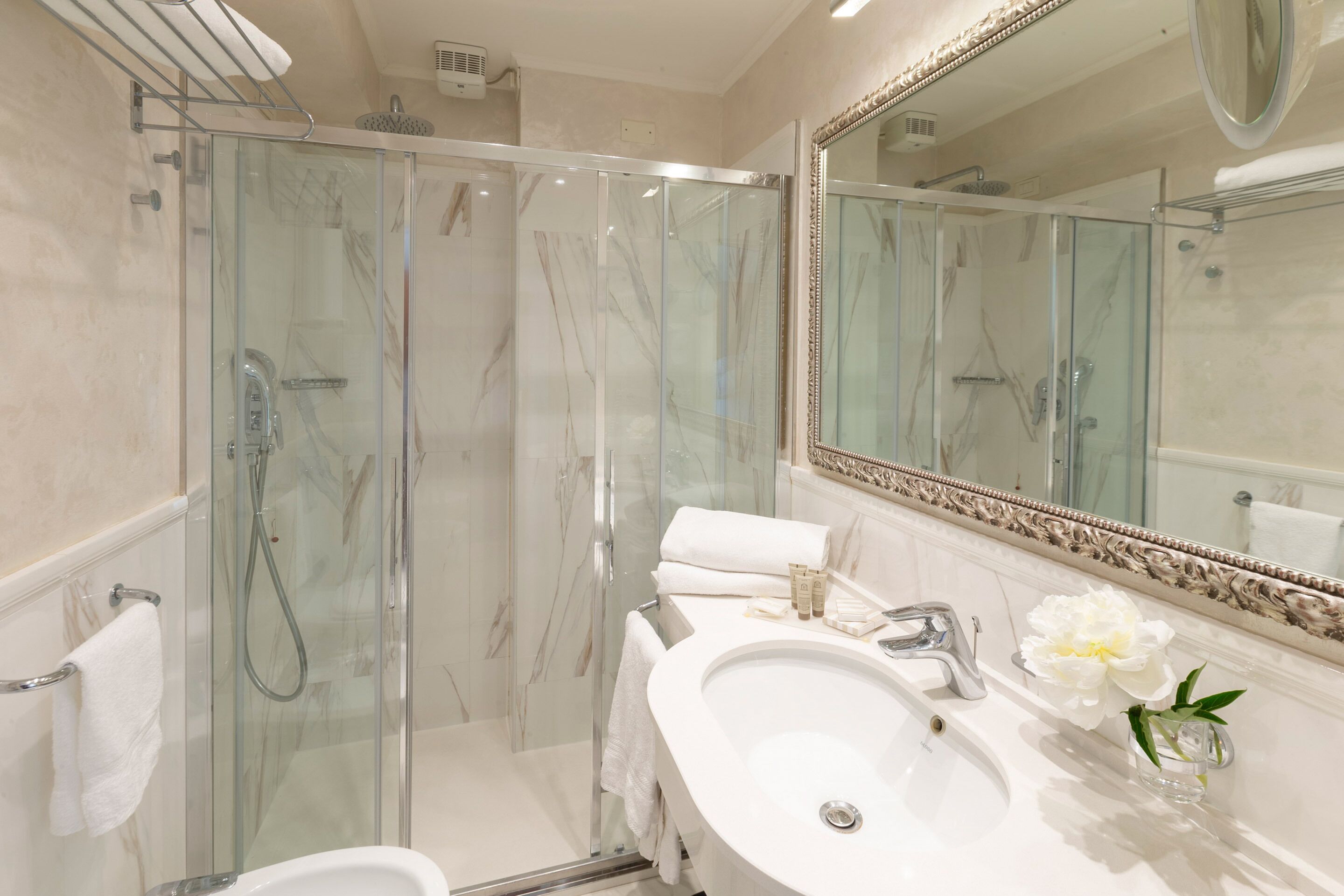 A modern bathroom with a glass-enclosed shower, a large mirror, and a white sink.