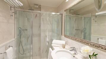 A modern bathroom with a glass-enclosed shower, a large mirror, and a white sink.