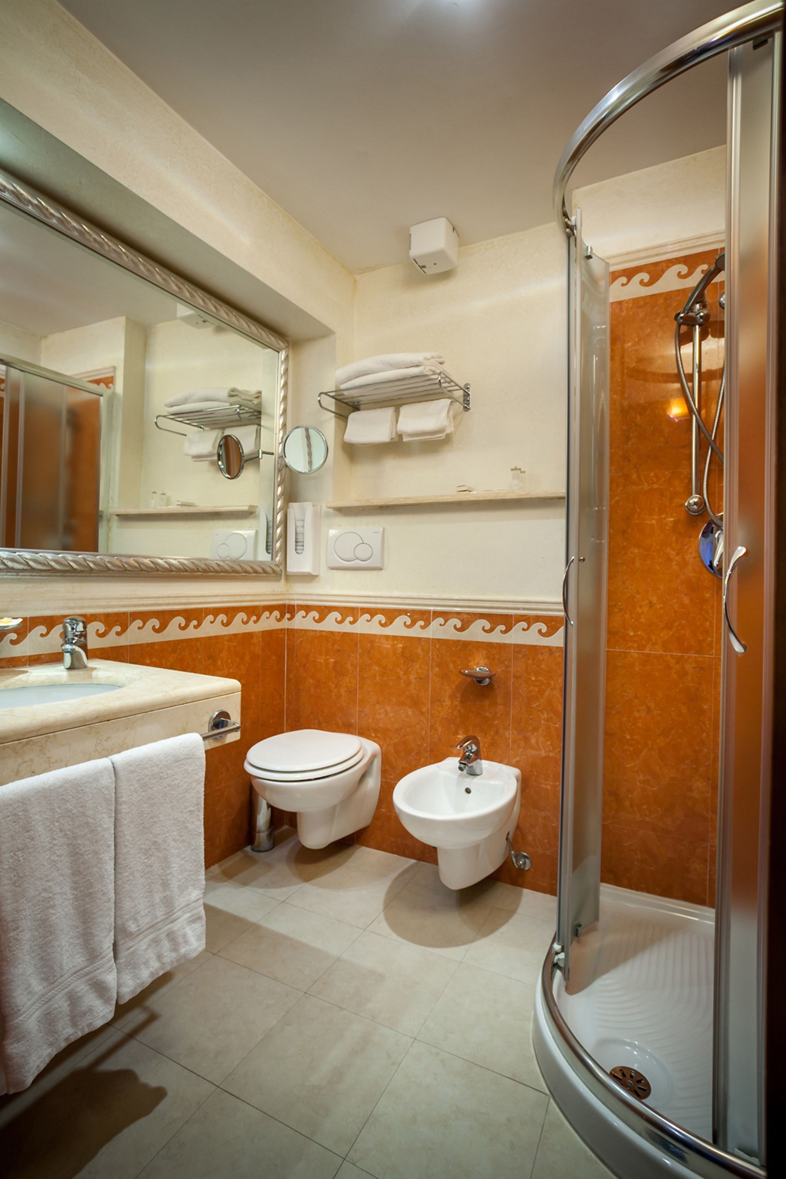 A bathroom with a sink, toilet, bidet, and a glass-enclosed shower.