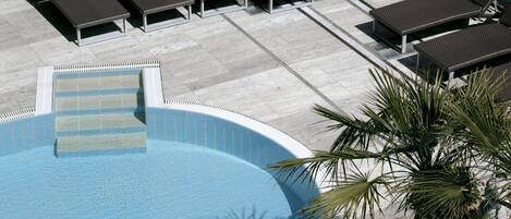 Ein Swimmingpool mit Liegestühlen und einer Palme.