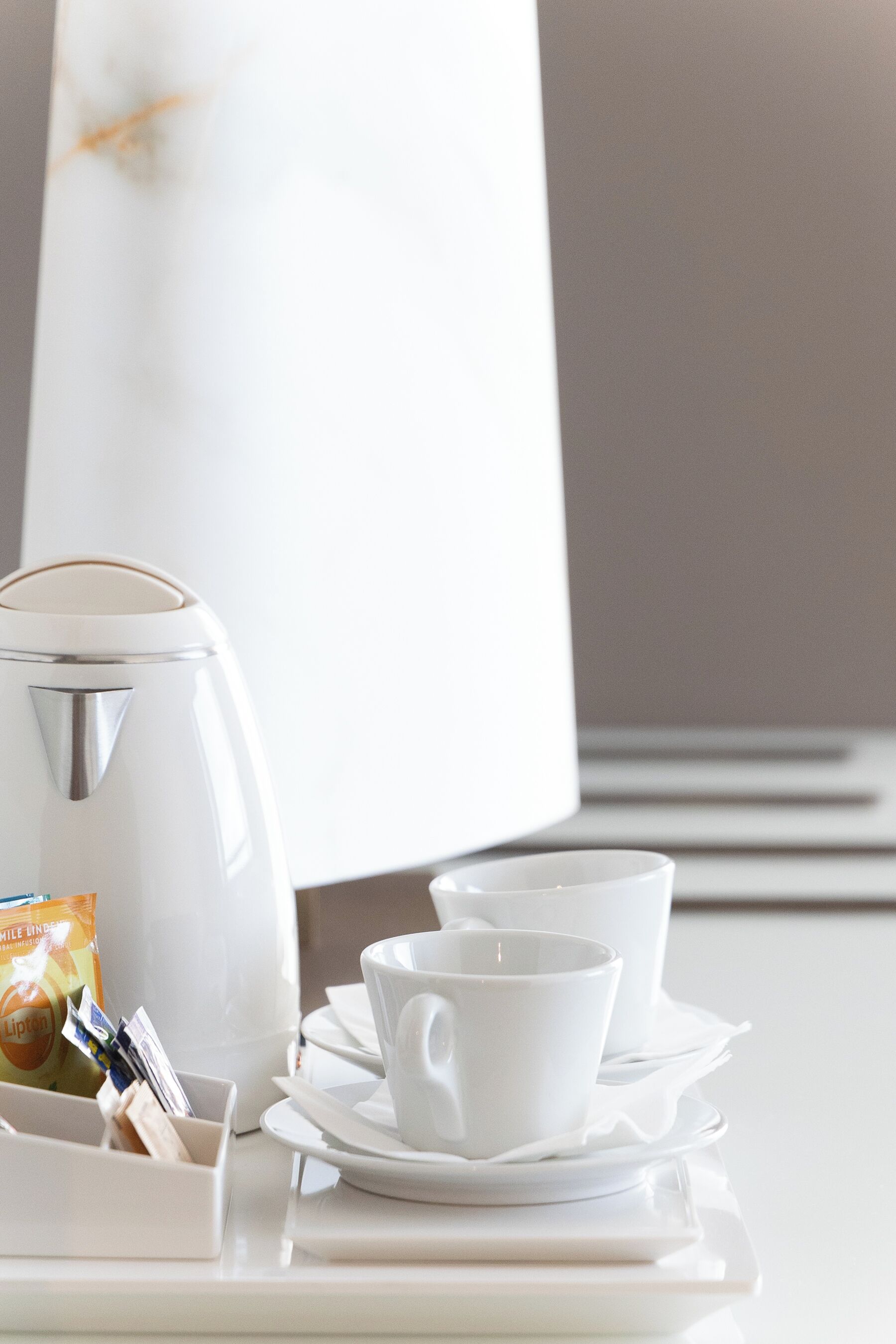 Une cafetière blanche, une tasse et une soucoupe sur un plateau.