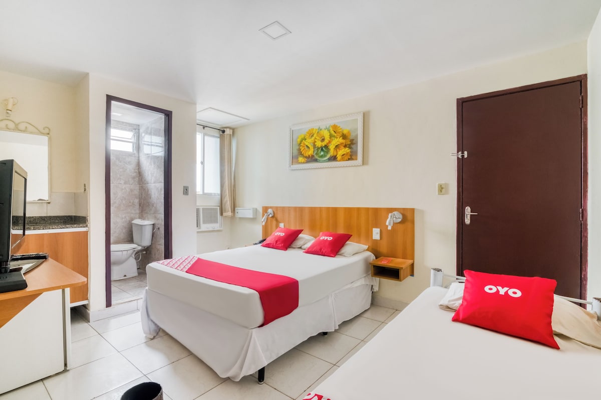 A hotel room with a bed, a desk, a television, a bathroom, and a door.