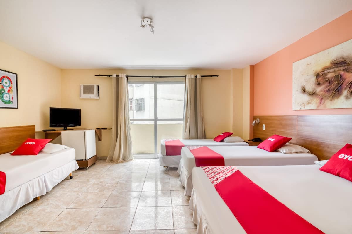 A hotel room with two beds, a television, a desk, and a window with curtains.
