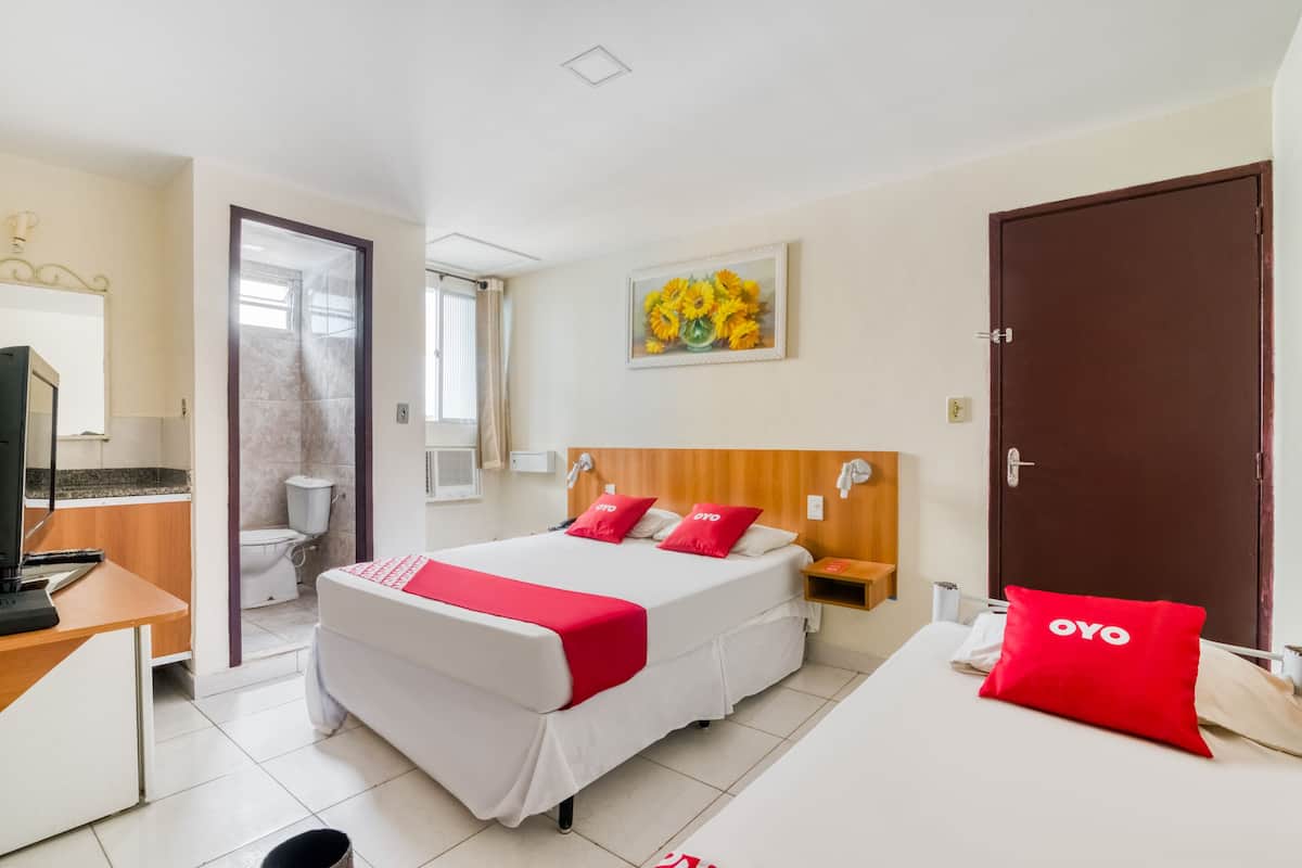 A hotel room with a bed, a desk, a television, a bathroom, and a door.
