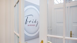 A hallway with a sign reading "Fritz AM BRUNNEN" and a door with a brass handle. - Fritz am Brunnen (Schwelm)