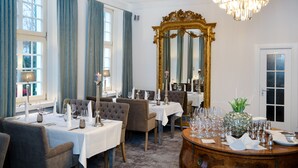 A formal dining room with tables set for service, a large ornate mirror, and a chandelier. - Fritz am Brunnen (Schwelm)