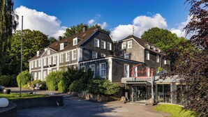 A large, historic building with a classic architectural style, featuring multiple windows and a prominent entrance with a glass facade. - Fritz am Brunnen (Schwelm)