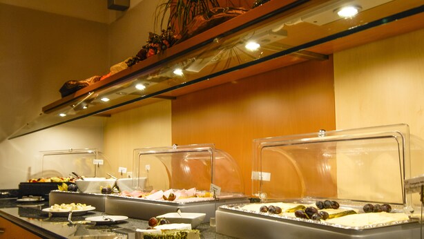 Buffet amb diversos aliments, com ara formatge, fruita i carn, exposats en recipients transparents.