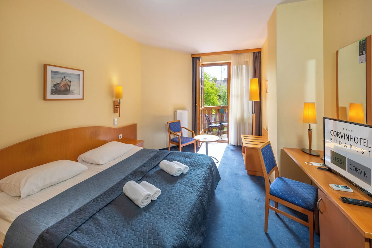 Habitación de hotel con una cama grande, un escritorio, una silla y vistas al exterior.