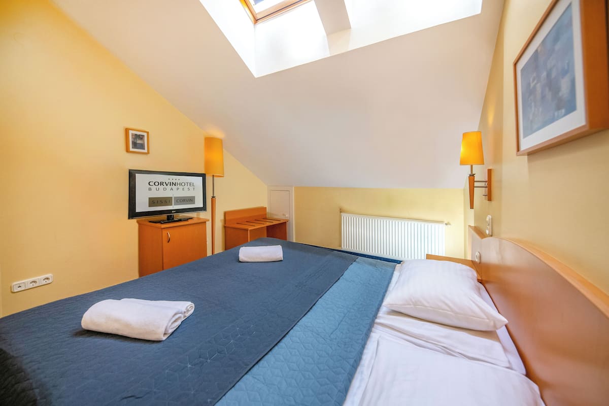 Habitación de hotel con cama, televisión, escritorio y ventana con vista a la ciudad.