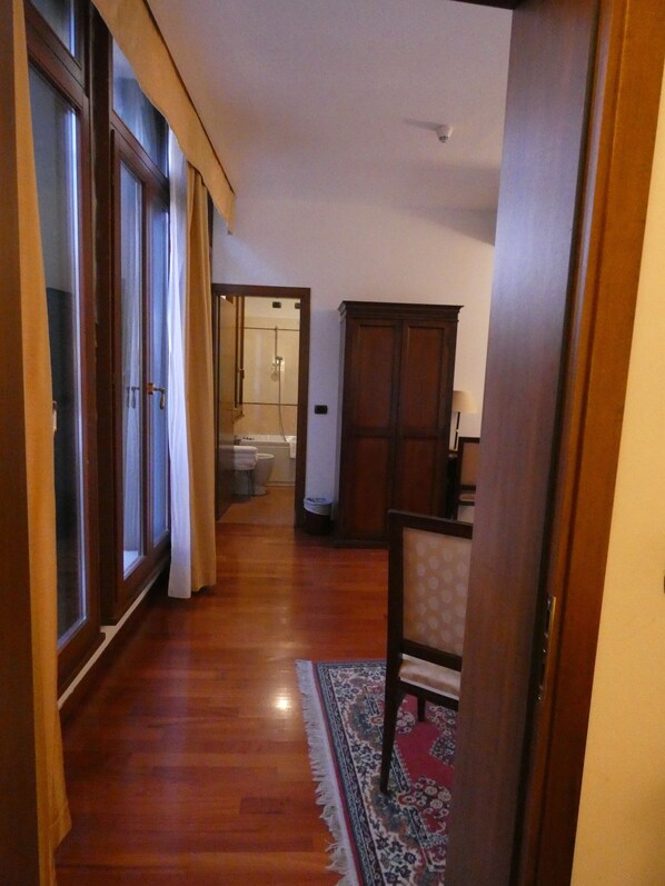 A hallway with wooden flooring, a large wooden cabinet, and a patterned rug.