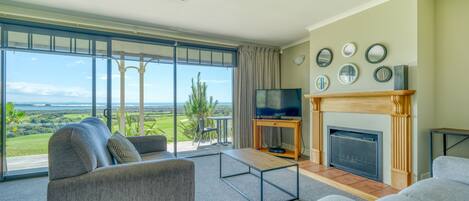 Una sala de estar amplia con un gran ventanal, chimenea y televisor.