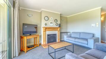Ein Wohnzimmer mit Kamin, Fernseher, Sofa und Couchtisch.