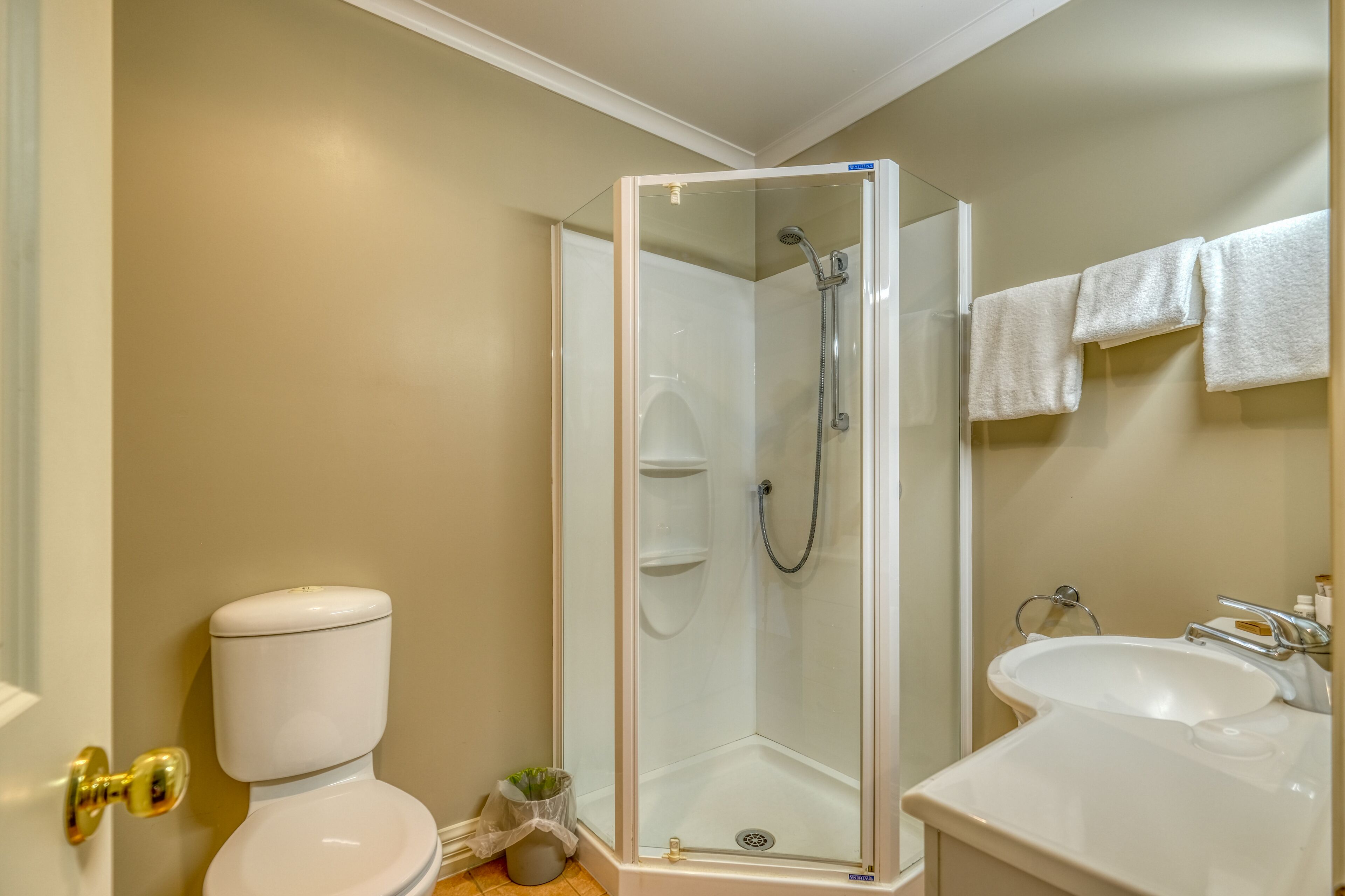 A bathroom with a toilet, a glass-enclosed shower, and a sink.