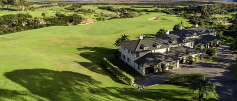 A large house with a well-maintained lawn and a golf course in the background.