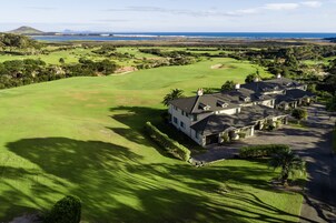 Una casa grande con un césped cuidado y un campo de golf al fondo.