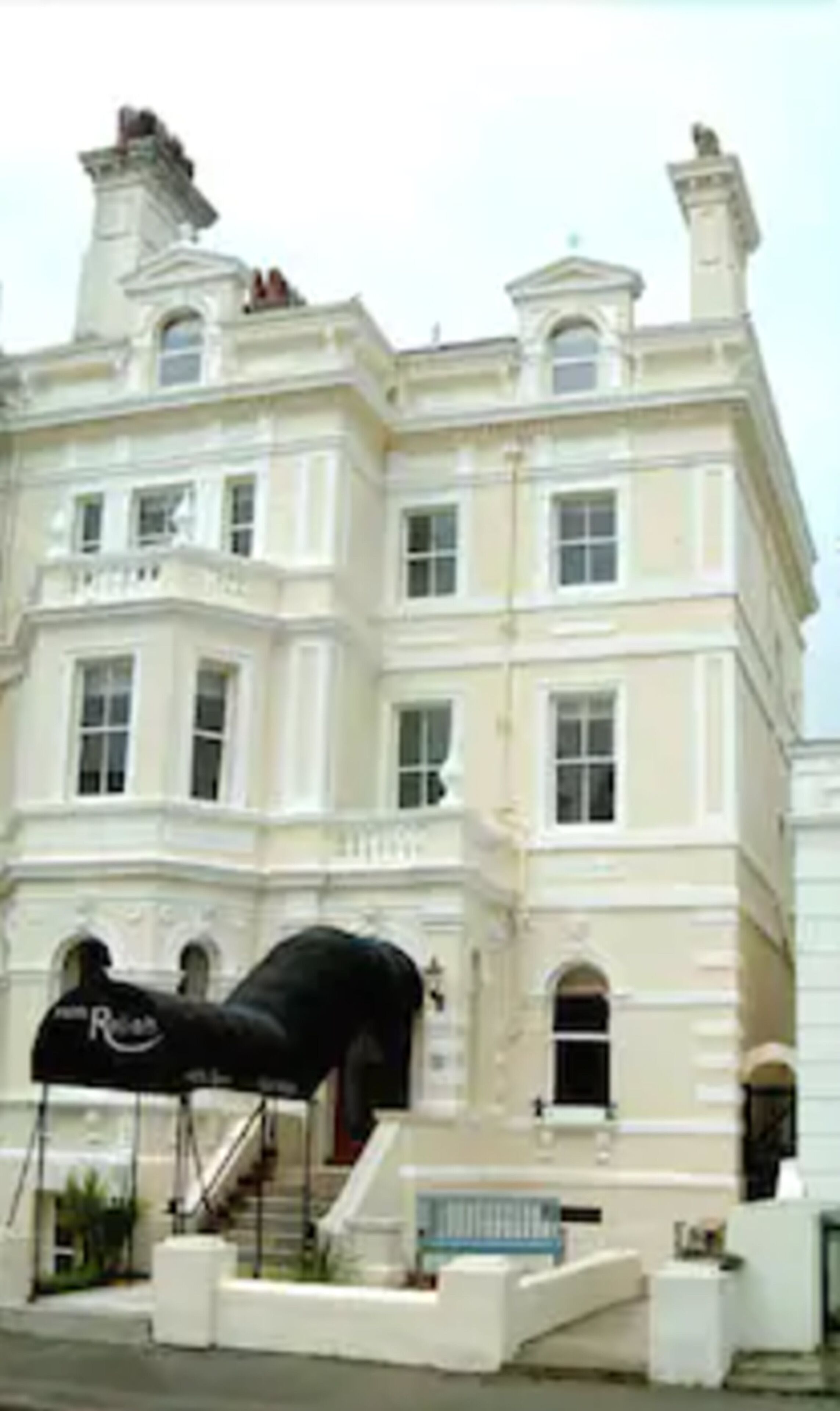 A large, white, classical-style building with multiple windows and a prominent entrance.