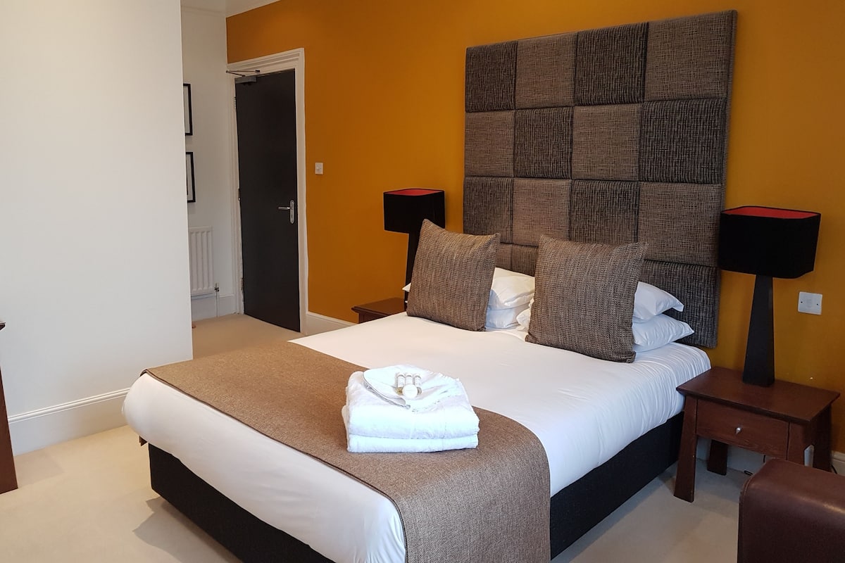 Quarto bem arrumado com uma cama grande, duas mesas de cabeceira, uma cabeceira e uma porta.