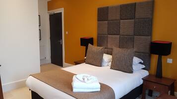 A neatly arranged bedroom with a large bed, two bedside tables, a headboard, and a door.