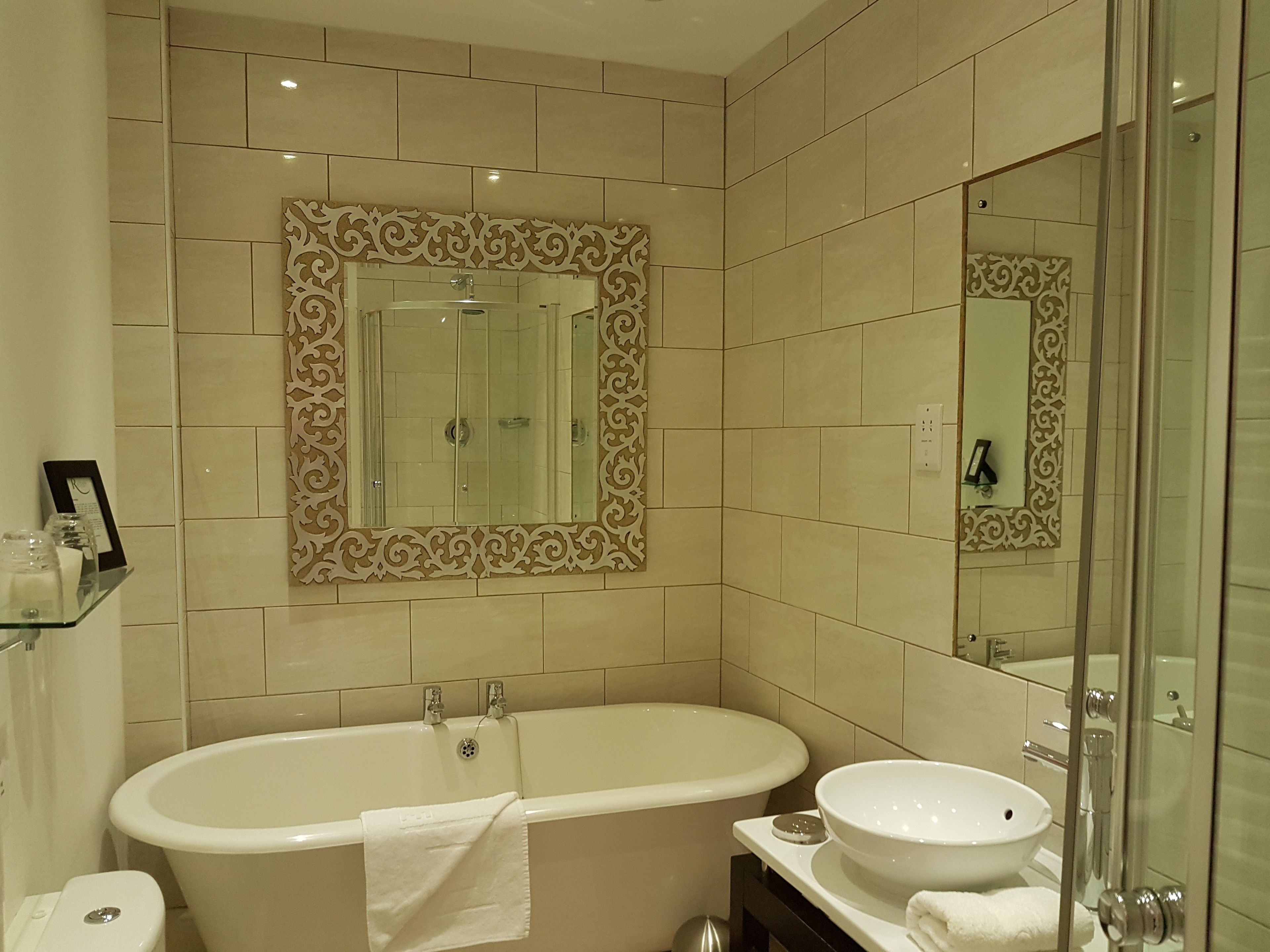 Ein Badezimmer mit einer freistehenden Badewanne, einem Waschbecken und einem großen Spiegel.