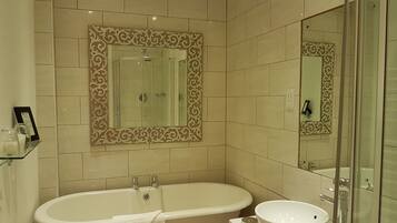 Ein Badezimmer mit einer freistehenden Badewanne, einem Waschbecken und einem großen Spiegel.