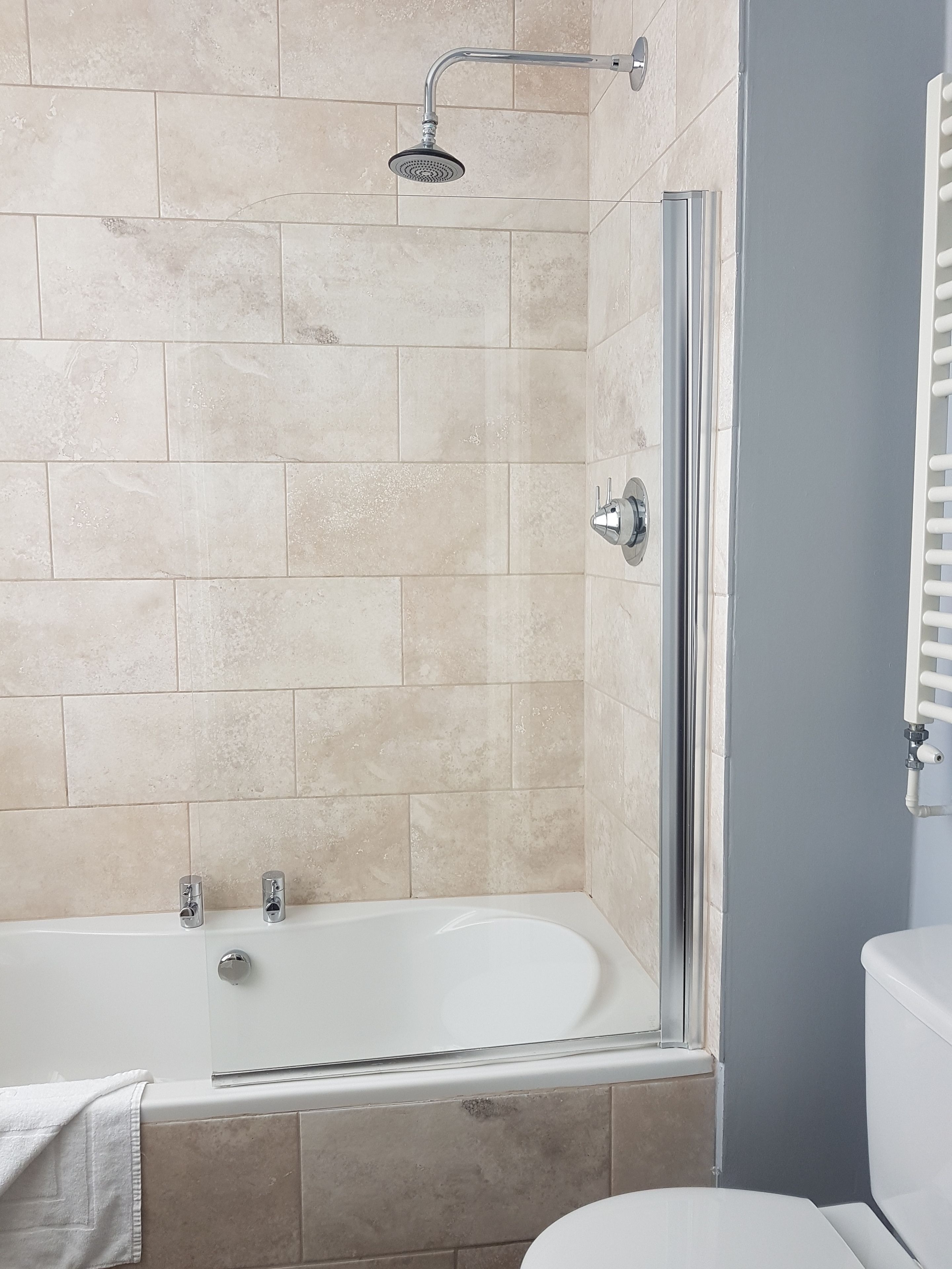 A bathroom with a bathtub, shower, and toilet.