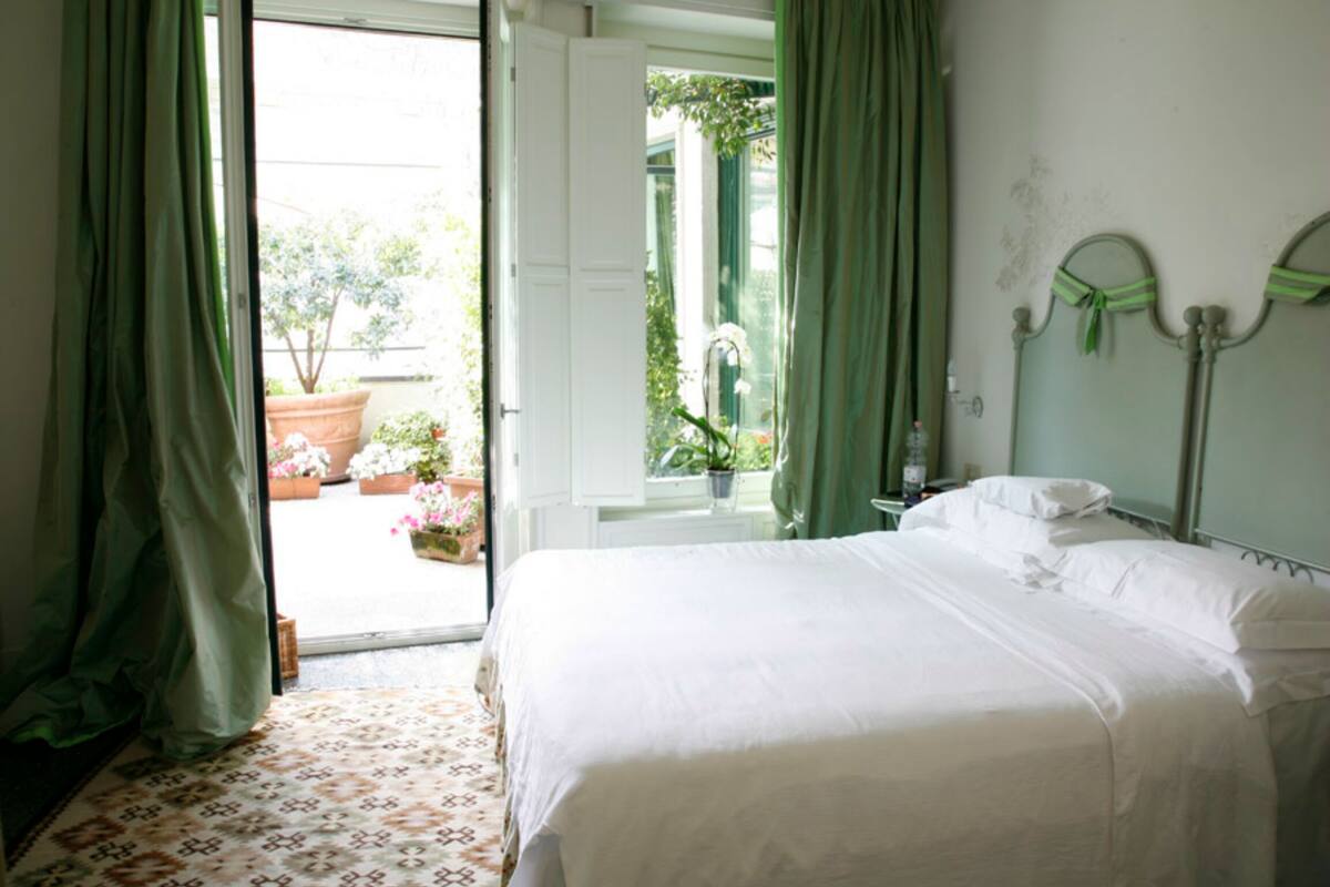 Een slaapkamer met een bed, nachtkastje en raam met gordijnen.
