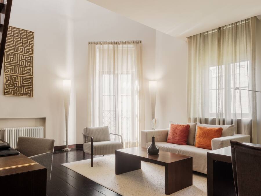 Una sala de estar moderna con un sofá, sillones, una mesita de centro y una lámpara de pie.