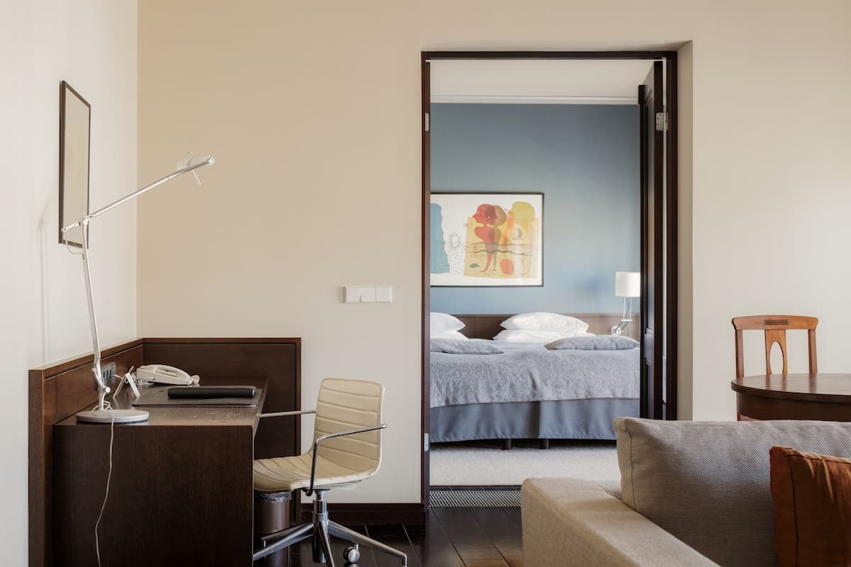 Un cuarto de hotel con escritorio, silla, cama y un cuadro en la pared.