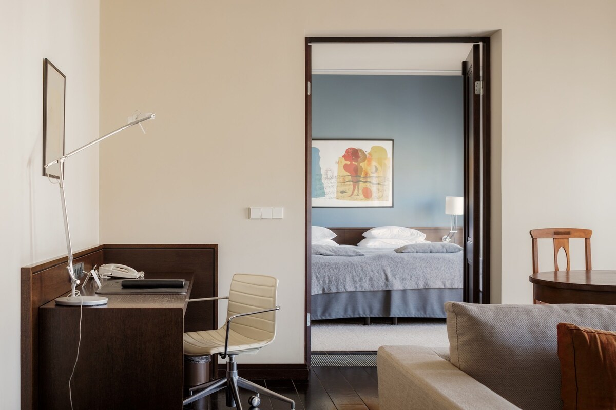 Ein Hotelzimmer mit Schreibtisch, Stuhl, Bett und einem Bild an der Wand.