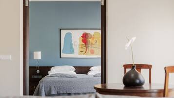 Una habitación de hotel con una cama, una mesita de noche con un florero y una lámpara de pared.