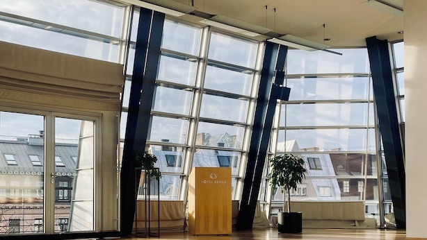 A spacious hotel lobby with large windows, a wooden floor, and a reception desk labeled "HOTEL BERGS". - Hotel Bergs Suites (Riga)