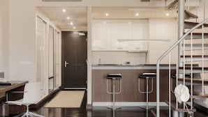 A modern kitchen with a dark wood floor, a stainless steel staircase, and a minimalist design. - Hotel Bergs Suites (Riga)