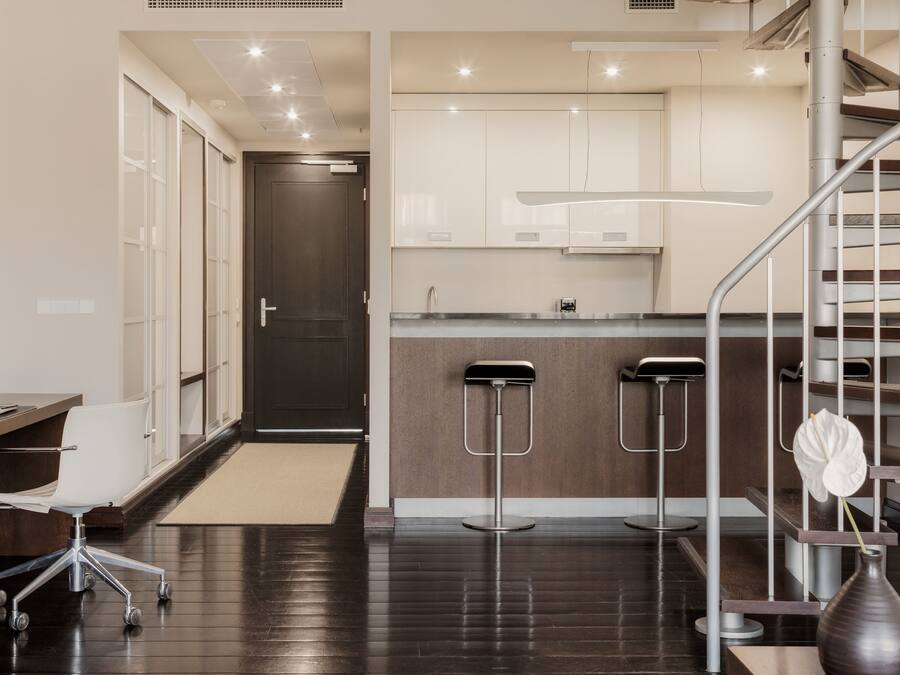 Una cocina moderna con una isla central, un comedor con una trona y una escalera.