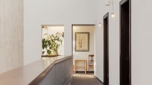 A modern interior with a glass ceiling, a wooden bench, and a framed artwork on the wall. - Hotel Bergs Suites (Riga)