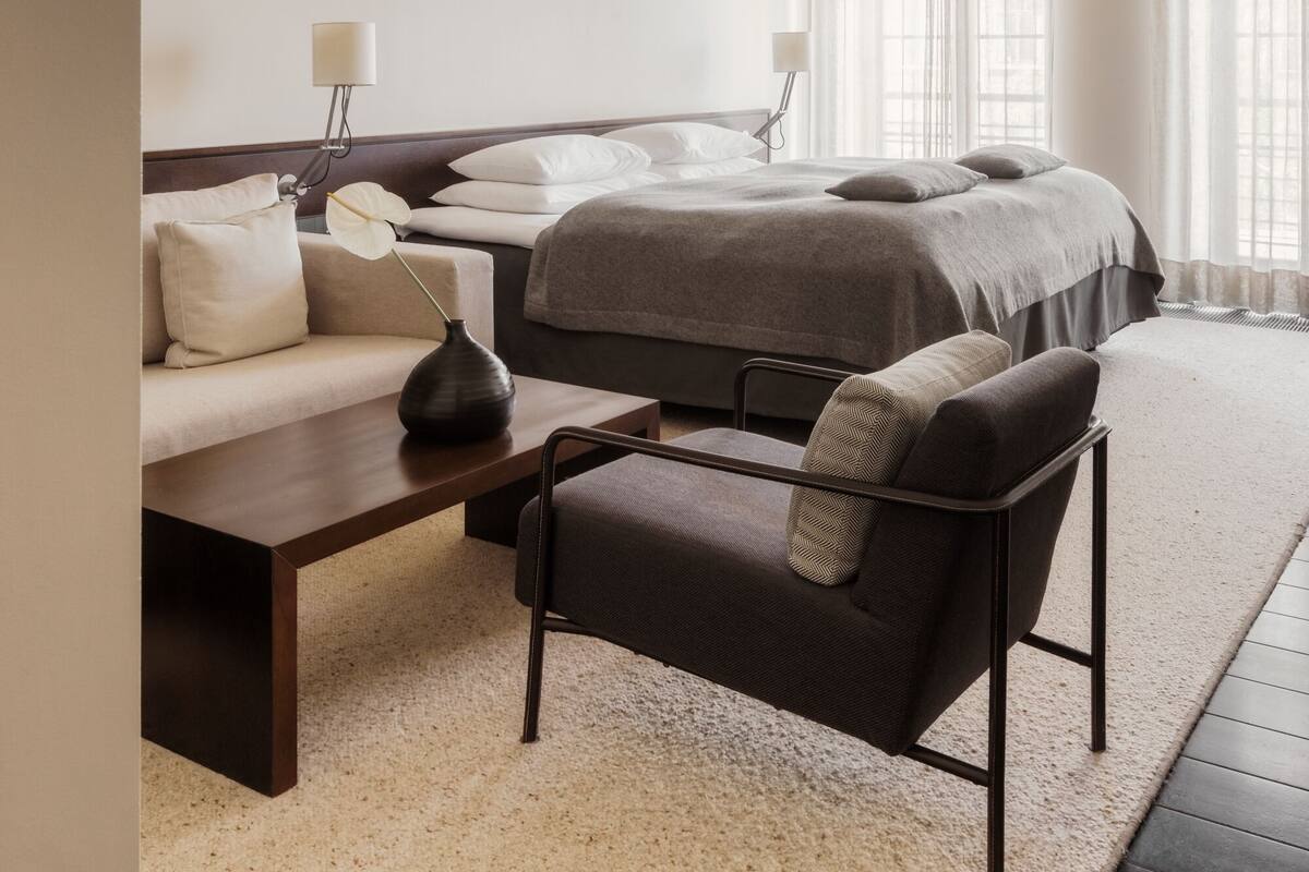 Una habitación de hotel moderna con una cama grande, un sofá, un escritorio y una silla.