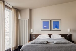 Relax in a serene space with a large bed, framed artwork, and comfortable bedside lamps.