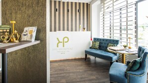 Un espace d’accueil comprenant un comptoir de réception, un canapé bleu et un mur orné d’un logo.
