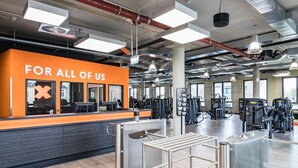 Une salle de sport avec un mur orange bien visible et une pancarte sur laquelle on peut lire : « POUR NOUS TOUS ».