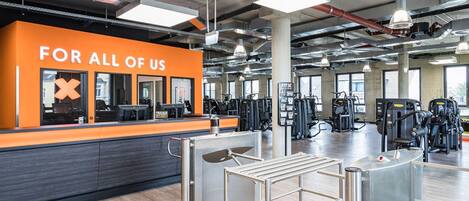 A gym with a prominent orange wall and a sign that reads "FOR ALL OF US".