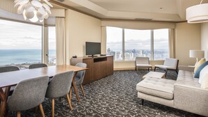 A hotel room with a city view, a dining area, a sofa, and a TV. - The Buckingham Hotel (Chicago)
